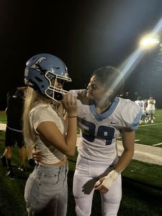 a man and woman standing on top of a football field next to eachother