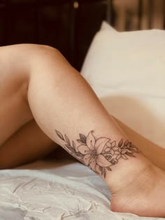 a woman laying on her stomach with a flower tattoo on her leg