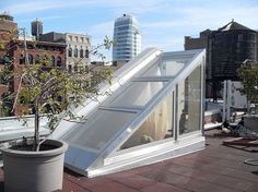 an open roof window on top of a building with a tree in the foreground