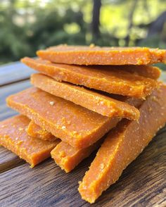 several pieces of orange colored food sitting on top of a wooden table next to trees