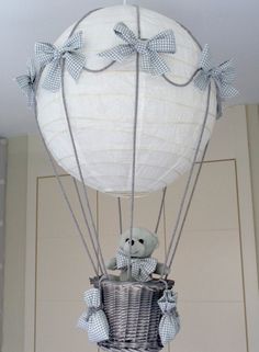 a teddy bear in a basket attached to a hot air balloon