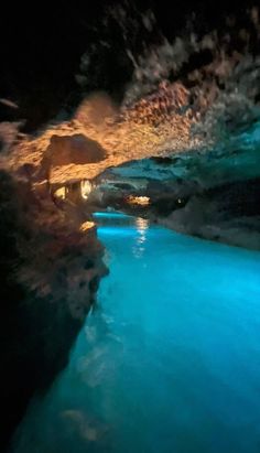 the inside of a cave is lit up with blue lights and water running through it