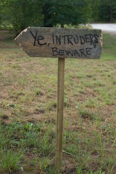 a sign that says ye, intruder beware on it in the grass