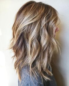 the back of a woman's head with long wavy hair and bangs on it