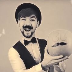 a man with a mustache holding an odd looking object in his hand and smiling at the camera