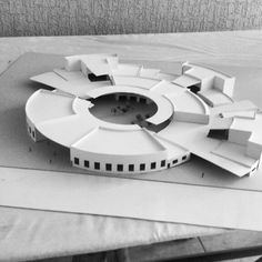 a model of a circular building on top of a wooden table in black and white