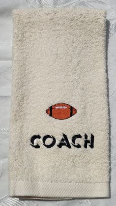 a white towel with an orange football on it and the word coach written in black