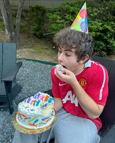 a young man sitting on a bench eating a birthday cake