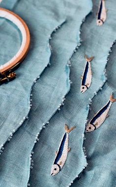 a close up of a piece of cloth with fish on it and a hoop hanging from the side