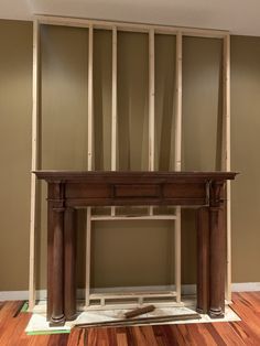 an empty room with a fireplace in the middle and wood framing on the wall behind it