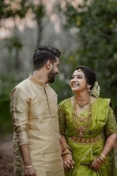 a man and woman standing next to each other in the woods