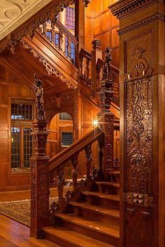 an ornate wooden staircase with carved wood paneling and handrails, leading to the second floor