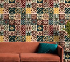 a couch sitting in front of a wall covered in colorful tile tiles and green plants