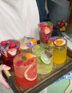 there are many drinks on the tray and one person is holding it in his hand