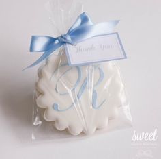 a white cookie wrapped in plastic with a blue ribbon