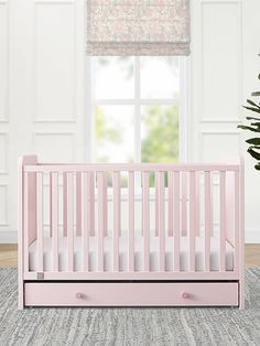 a pink crib in front of a window with blinds on the windowsill and a potted plant next to it