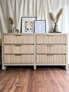 a dresser with two drawers and pictures on top of it in front of a curtain