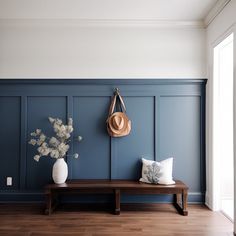 a wooden bench sitting next to a wall with a hat hanging on it's side