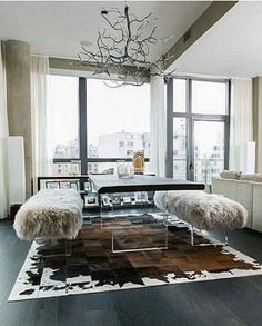 a modern living room with large windows and an area rug that looks like sheepskin