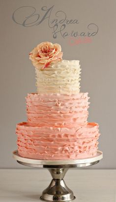 a three tiered cake with pink, white and orange icing on a silver plate