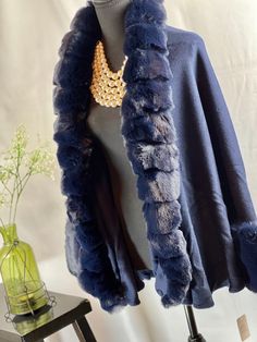 Upgrade your winter wardrobe with this chic navy blue cape. Made from a luxurious blend of wool and acrylic, it features a stylish faux fox fur trim that wraps around the neck and cascades down the front for added warmth. The open front style adds an element of sophistication to this piece. This cape exudes elegance with its faux fur trim that gives it a high-end look. The two-tone gradient color adds a unique touch, making it the perfect accessory to wear with jeans or leggings for any occasion. The voluminous faux fur adds a layer of style and is a must-have for those cold winter months. Not only is this cape perfect for fashion outings, but it's also ideal for casual wear, holiday festivities, shopping, dates, and any evening party. You can even wear it to your prom or as a bridal cover Elegant Blue Party Outerwear, Luxury Blue Outerwear For Evening, Luxury Blue Evening Outerwear, Winter Evening Capelet, Elegant Blue Shawl For Fall, Elegant Blue Fall Shawl, Elegant Winter Capelet, Blue Winter Outerwear For Evening, Elegant Evening Winter Capelet