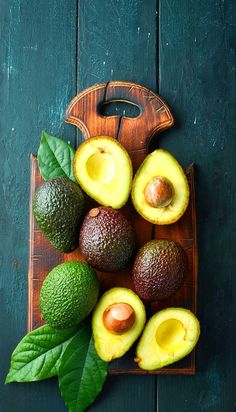 avocados on a cutting board with leaves