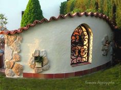 a small house with an arched window on the side and plants growing out of it