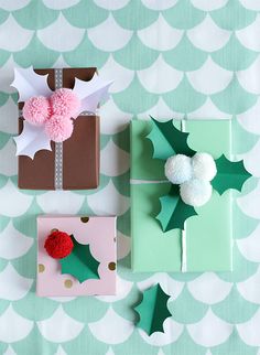 presents wrapped in green and pink paper with pom - poms