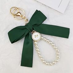 a key chain with pearls and a green bow