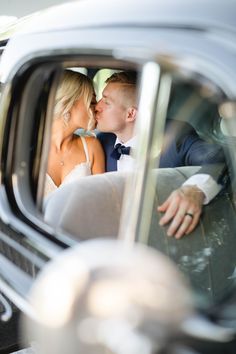 a bride and groom kissing in the back seat of a car