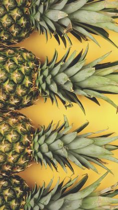 several pineapples are arranged on a yellow background