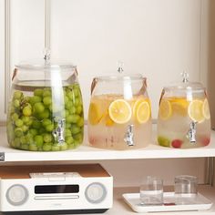 three jars with lemons, grapes and water on a shelf next to a radio