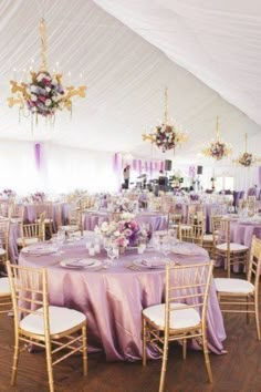 the inside of a tent with tables, chairs and chandeliers set up for an event