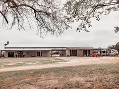 a large building with two trucks parked in front of it and a tree near by