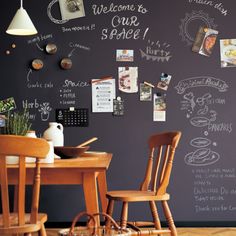 a chalkboard wall with writing on it and wooden chairs in front of the table