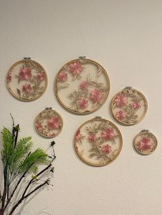 the wall is decorated with pink flowers and gold trimmings, which are hanging above a potted plant