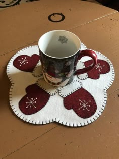 a coffee cup sitting on top of a table next to a mug cozying mat