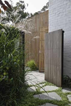 a wooden fence next to a white brick wall and green grass in front of it