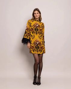 The Vida Dress in Dust Gold Fleur by Cara Cara is a striking mini dress featuring a feather trim, mock neck, and long sleeves. Invisible back zip with hook-and-eye closure Fully unlined 96% Viscose 4% Spandex, Stretch Crepe Made in China Front has bust darts for fitted look #1096