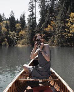 a woman is sitting in a boat with a camera