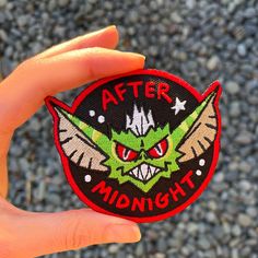 someone holding up a patch that says, after midnight with an evil face on it