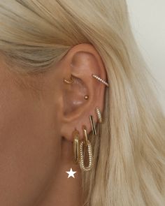 a woman with blonde hair wearing three different ear piercings and one has a star on it