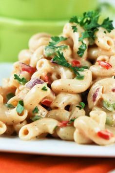 a white plate topped with macaroni salad next to a fork and green cup