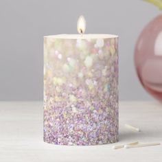 a candle that is sitting on a table next to some pencils and a vase