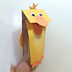 a hand holding up a paper bag with a chicken on it's head and tongue sticking out