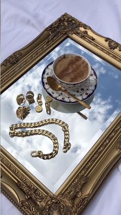 a gold frame with a cup of coffee on it and other items in the reflection