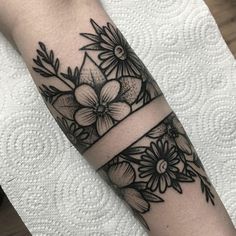 a black and white flower tattoo on the left arm with a ribbon around it's wrist