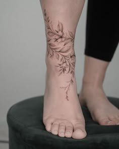 a woman's foot with a flower tattoo on her left ankle and the bottom part of her leg