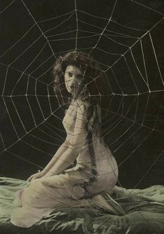 a woman sitting on top of a bed covered in spider web