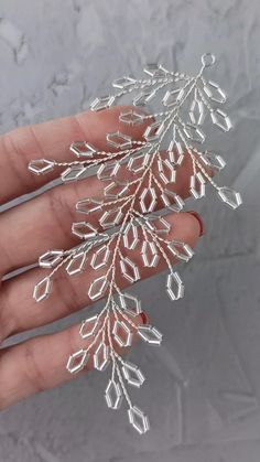 a hand holding a silver snowflake ornament on it's palm